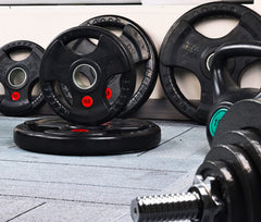 Signature Fitness plates mounted on an Olympic bar demonstrating secure load for compound lifts