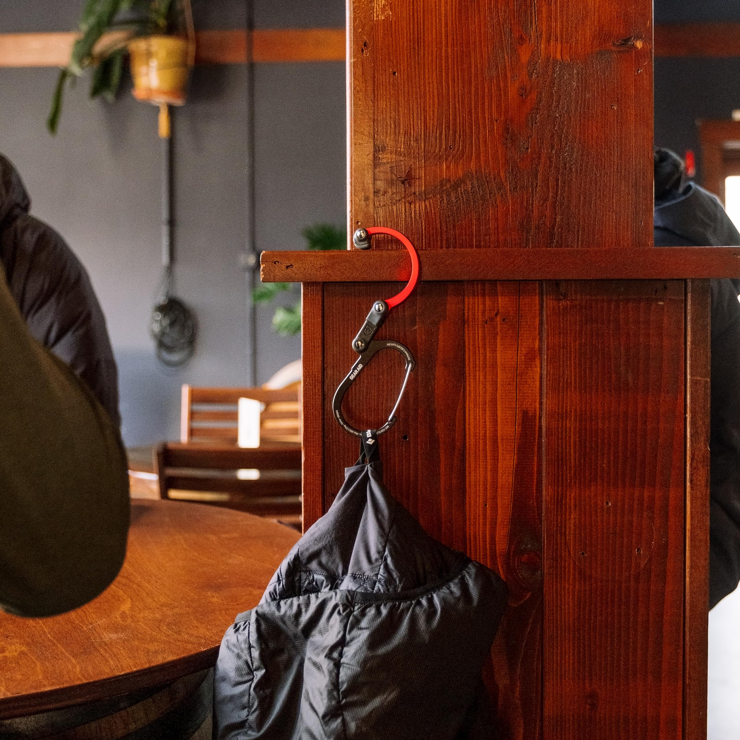 GEAR AID HEROCLIP hanging a carry-on in a bathroom stall for travel convenience