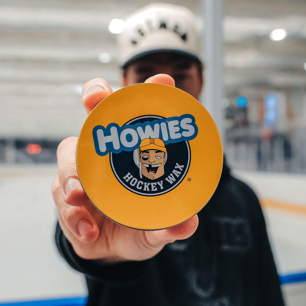 Howies wax next to hockey puck showing compact 2.8oz scale