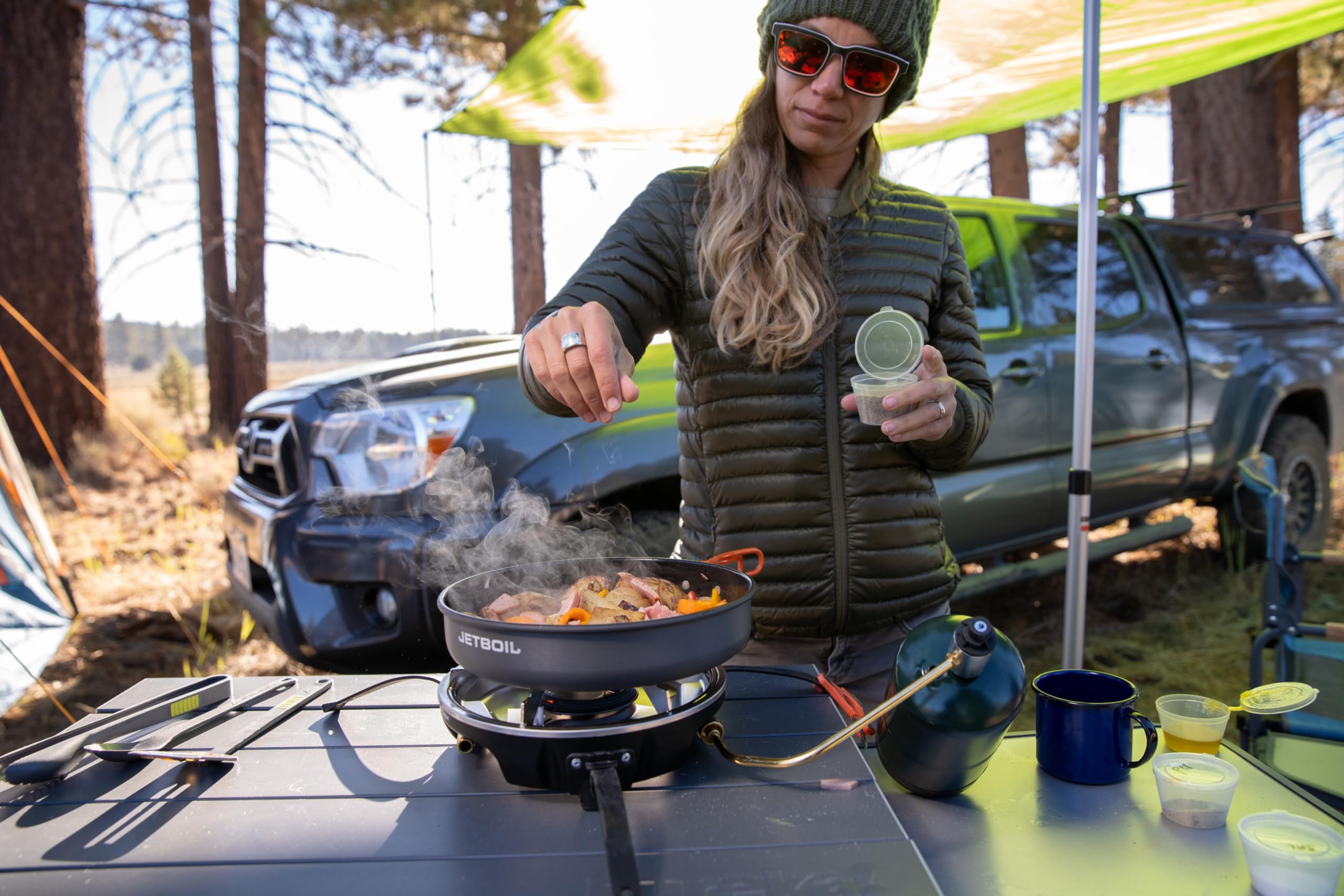 Jetboil HalfGen in a basecamp setting with cookware and food, conveying meal-ready convenience