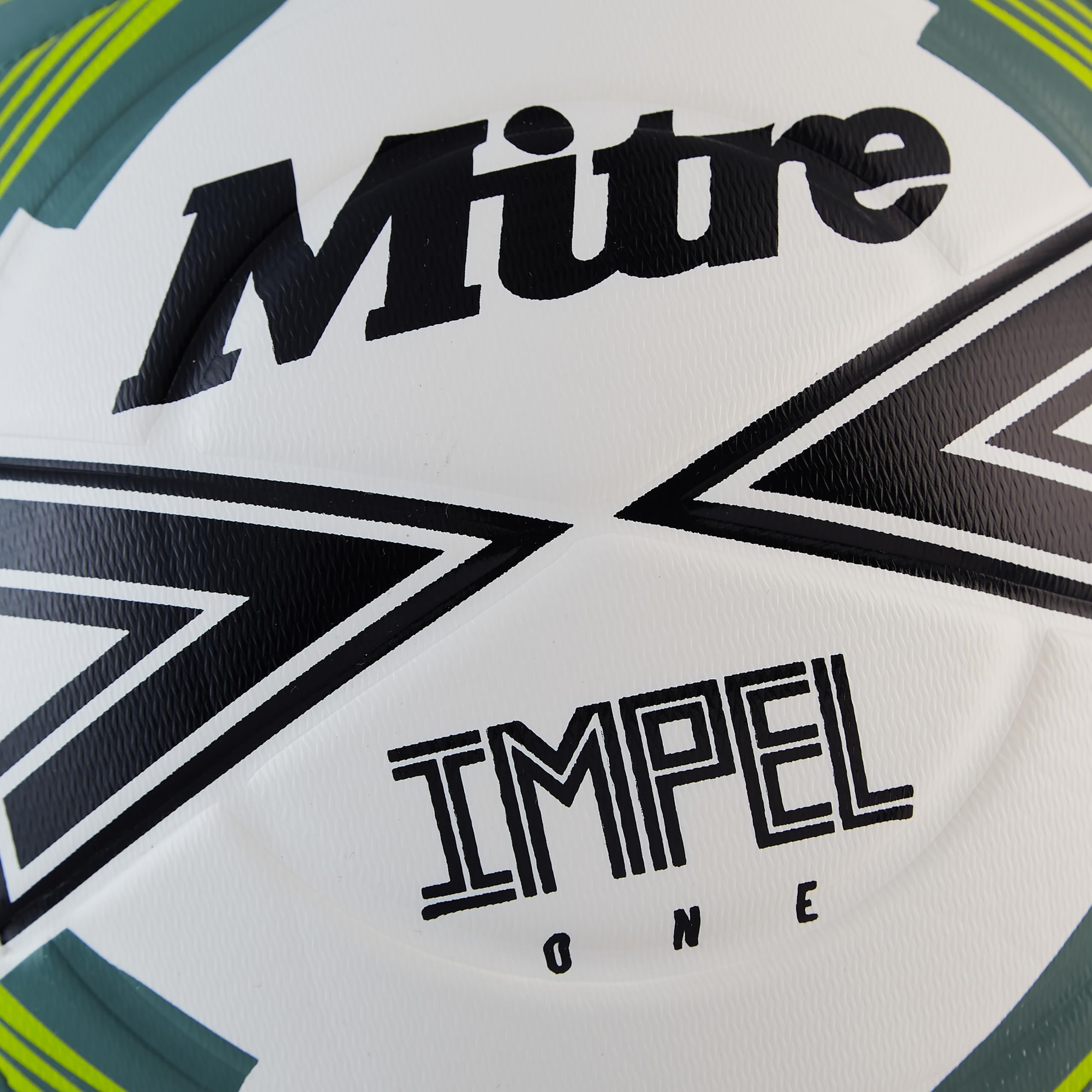 Mitre IMPEL ONE being kicked on grass demonstrating dependable performance outdoors
