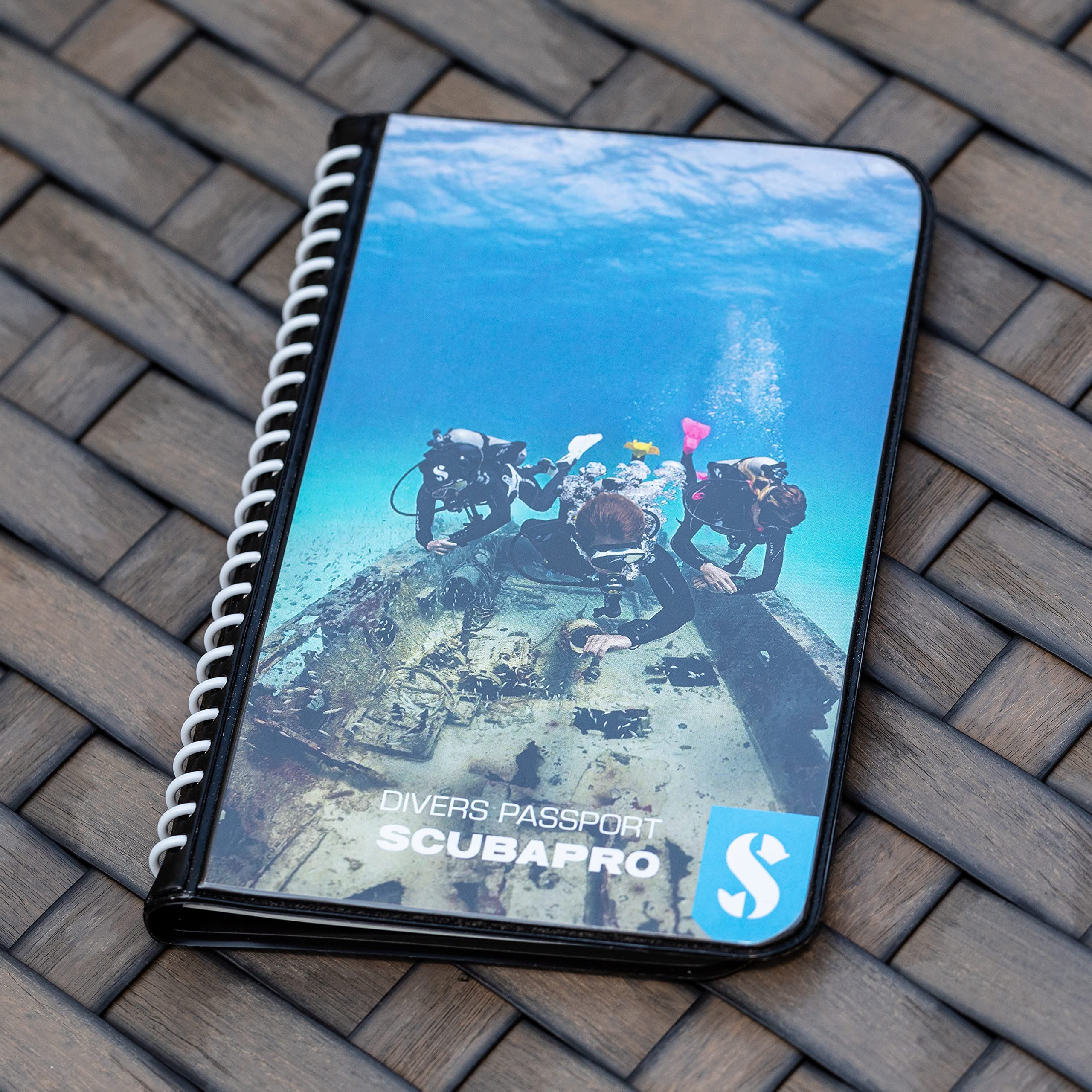 SCUBAPRO logbook in use on a boat with hands writing after a dive benefit