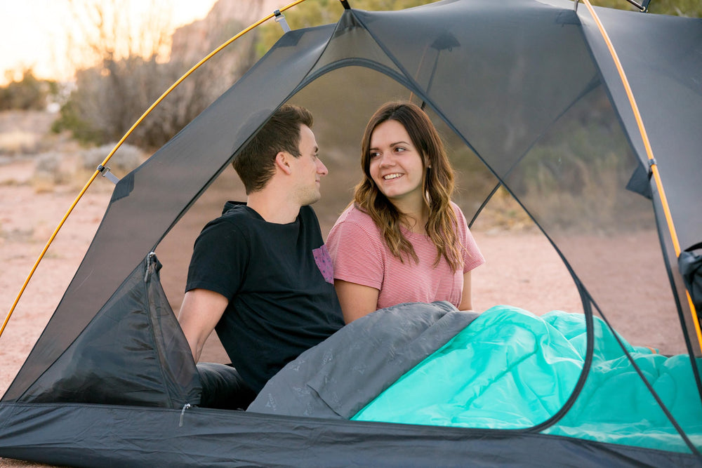 TETON Sports lifestyle at campsite with two people using bag for shared warmth and relaxation