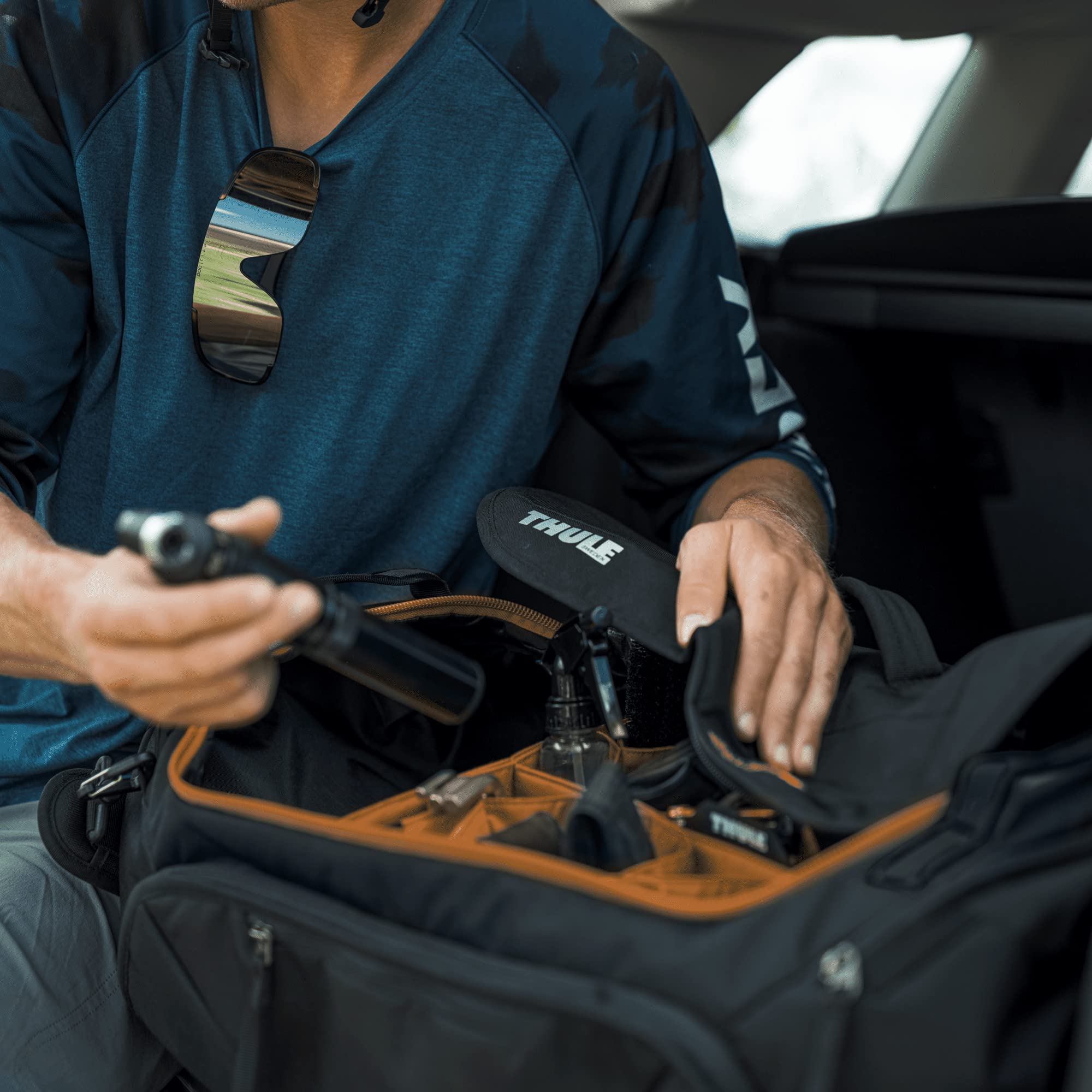 Thule RoundTrip next to a suitcase showing 55L capacity and packing utility