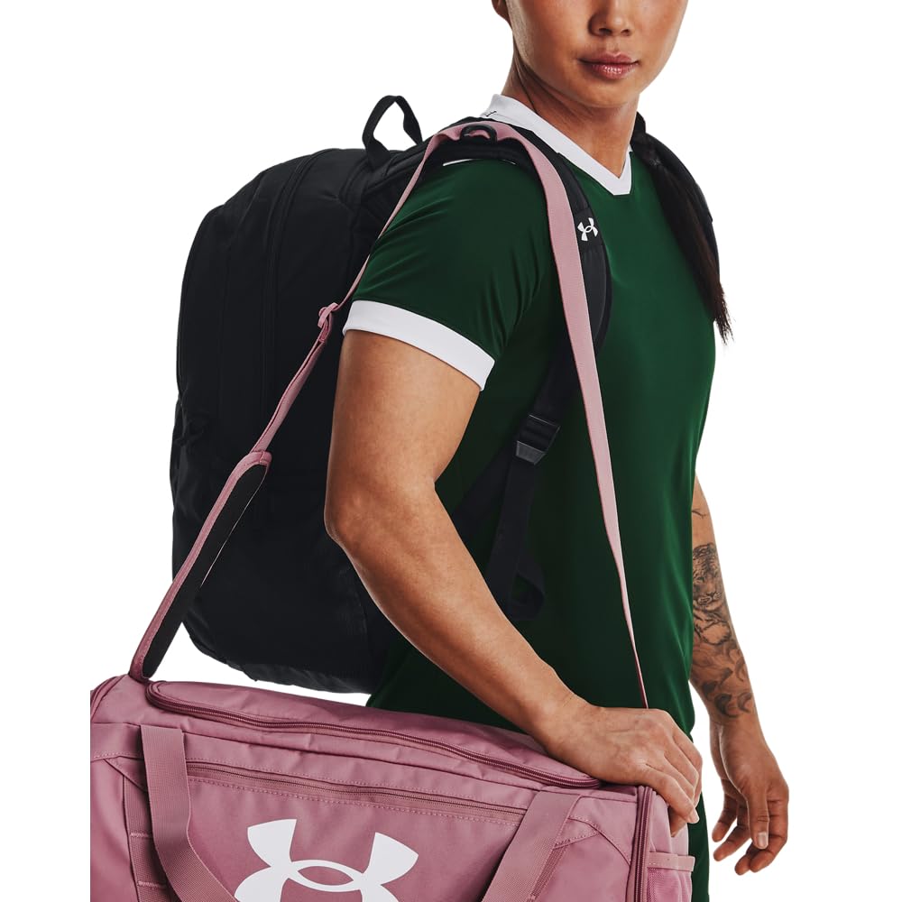 Under Armour backpack beside a football and sneakers to show size and multipurpose use