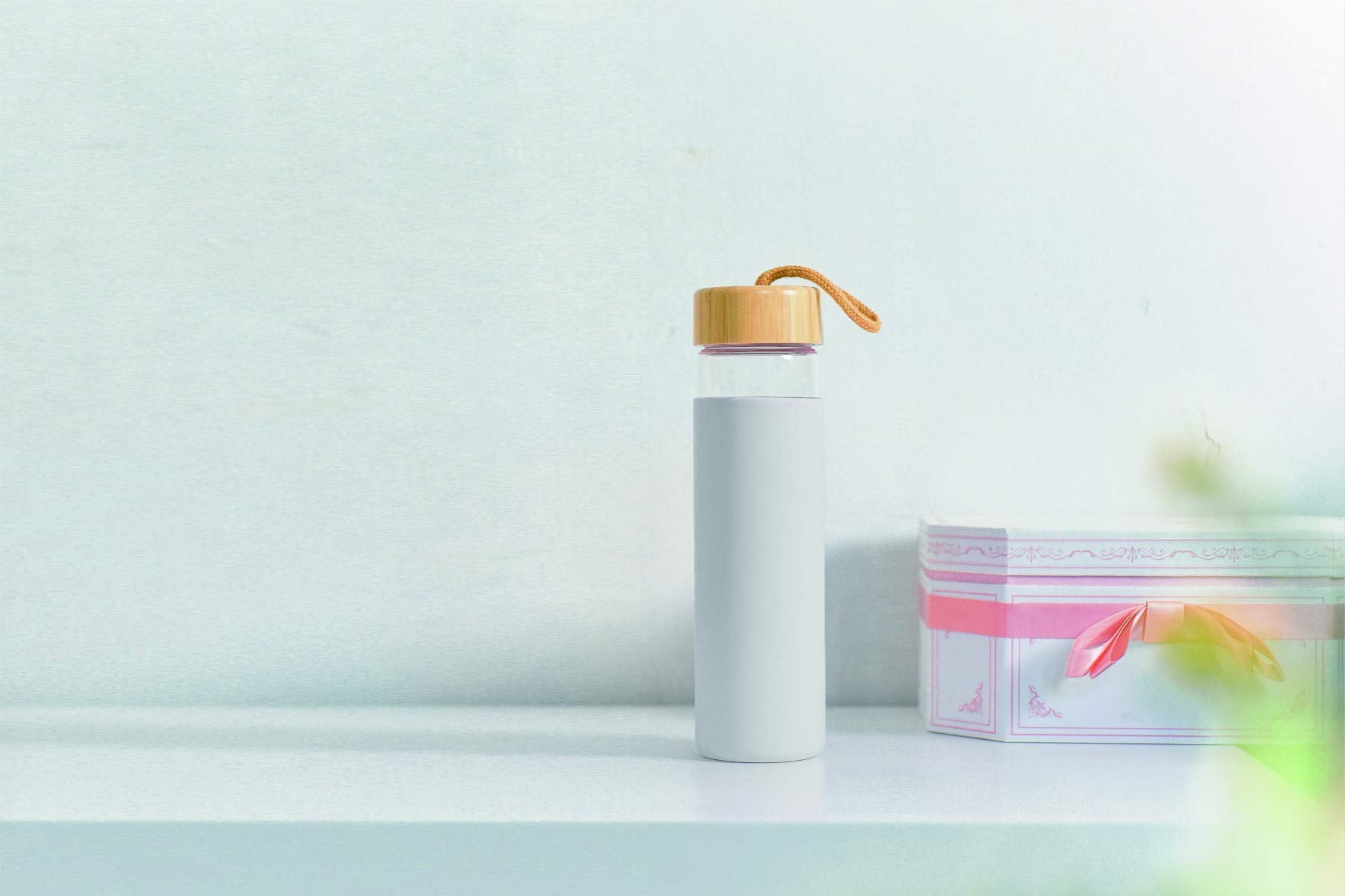 Yomious bottle beside phone showing 20 oz scale and portability benefit
