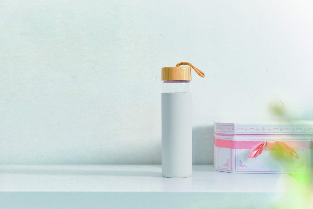 Yomious bottle beside phone showing 20 oz scale and portability benefit