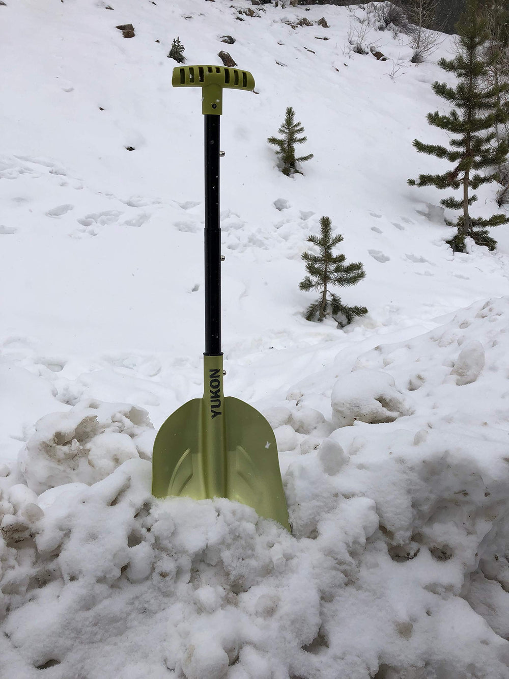 Yukon Charlie's shovel clearing snow at a campsite for quick setup